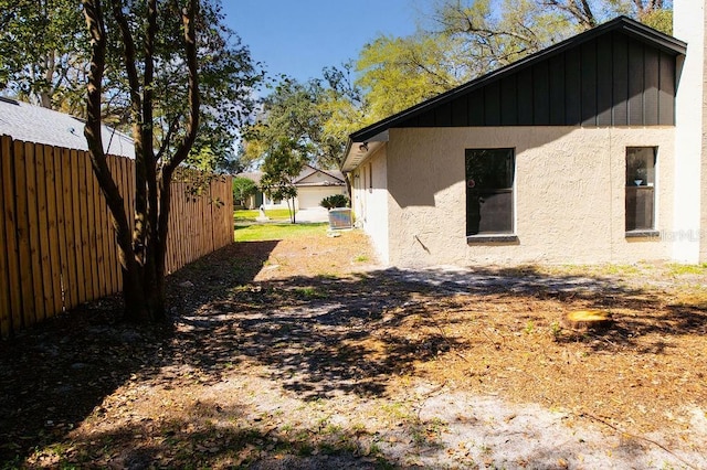 view of side of home featuring fence and stucco siding