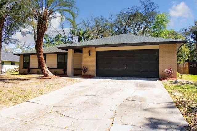 view of front facade featuring an attached garage, brick siding, a shingled roof, fence, and driveway