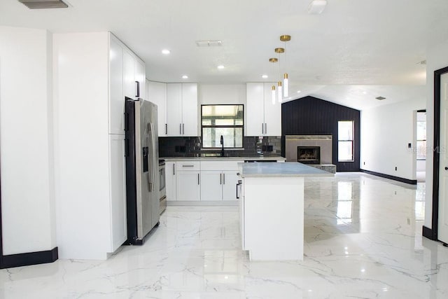 kitchen with stainless steel fridge with ice dispenser, open floor plan, marble finish floor, a center island, and tasteful backsplash