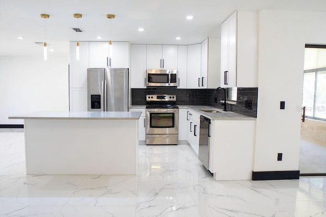 kitchen featuring marble finish floor, backsplash, appliances with stainless steel finishes, white cabinetry, and a sink