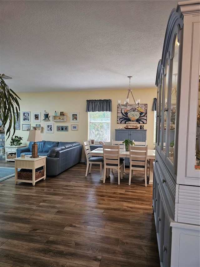 dining space featuring dark wood-type flooring, a chandelier, and a textured ceiling