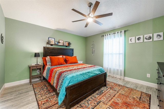 bedroom with light wood-style floors, baseboards, and a textured ceiling