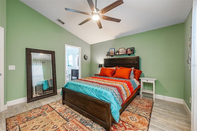 bedroom with baseboards, visible vents, ensuite bathroom, vaulted ceiling, and light wood-type flooring