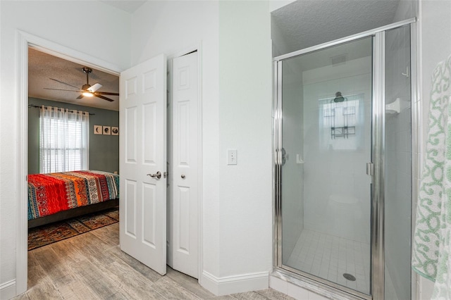 full bathroom featuring baseboards, connected bathroom, wood finished floors, a textured ceiling, and a shower stall