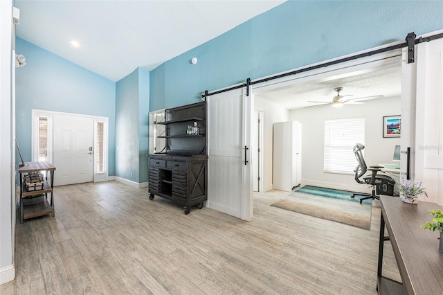 living room featuring a barn door, ceiling fan, vaulted ceiling, wood finished floors, and baseboards