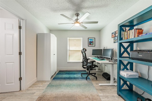 home office featuring a textured ceiling, wood finished floors, a ceiling fan, and baseboards