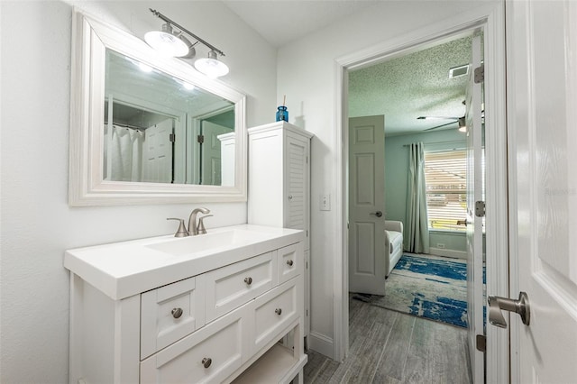 bathroom with a textured ceiling, wood finished floors, and vanity