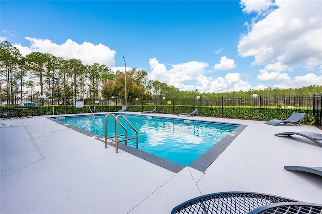 pool with a patio area and fence