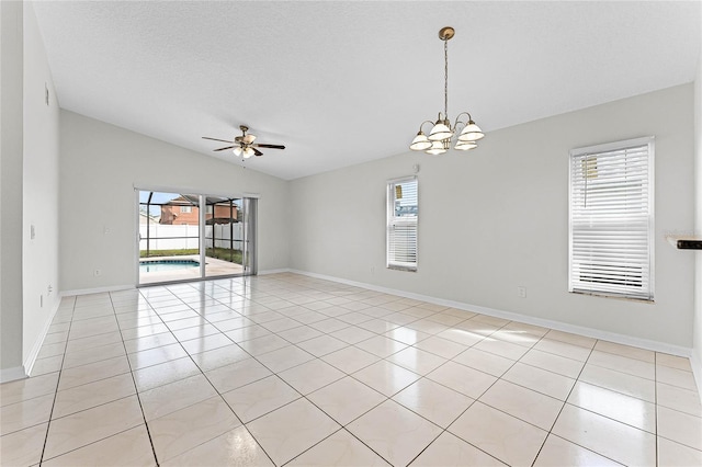 spare room featuring light tile patterned floors, a wealth of natural light, and ceiling fan with notable chandelier