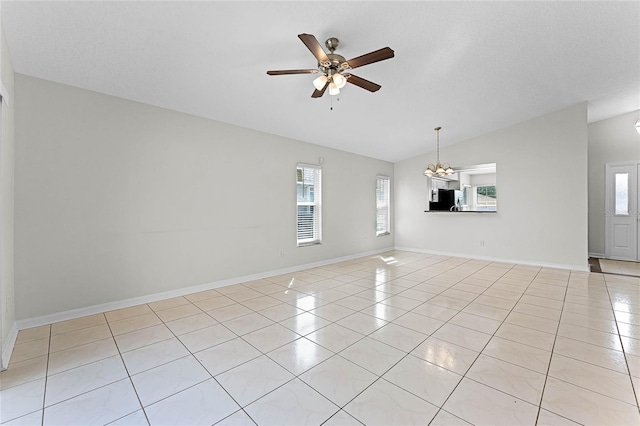 spare room featuring a wealth of natural light, lofted ceiling, light tile patterned flooring, and ceiling fan with notable chandelier