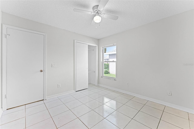 unfurnished room featuring a textured ceiling, light tile patterned flooring, a ceiling fan, and baseboards