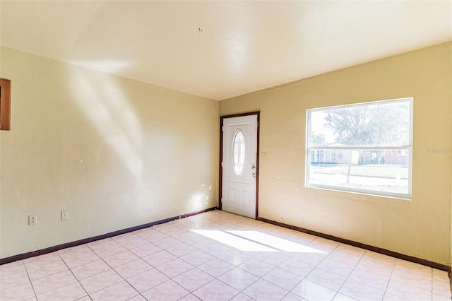 spare room featuring light tile patterned flooring and baseboards