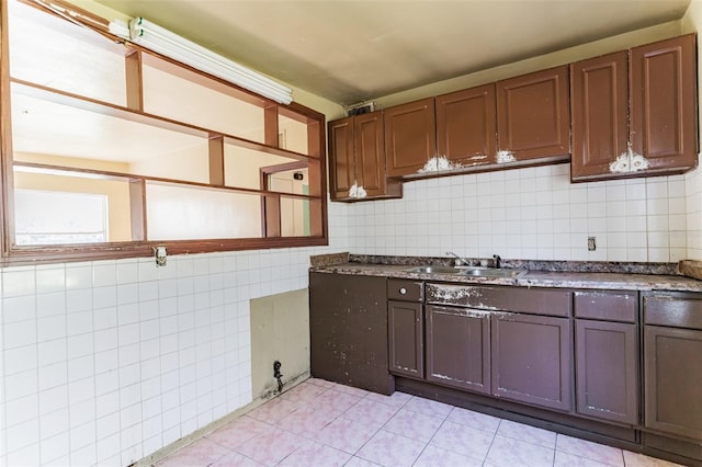 kitchen featuring tile walls, light tile patterned floors, dark countertops, backsplash, and a sink