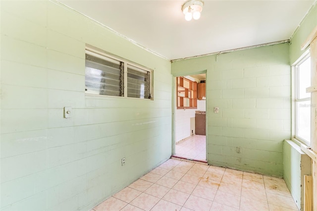 unfurnished room featuring concrete block wall and plenty of natural light