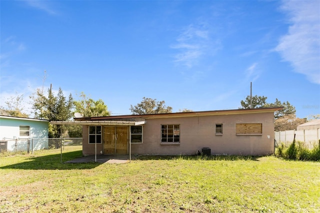 rear view of house with fence and a lawn