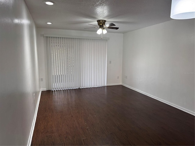 empty room with recessed lighting, dark wood-type flooring, a ceiling fan, a textured ceiling, and baseboards