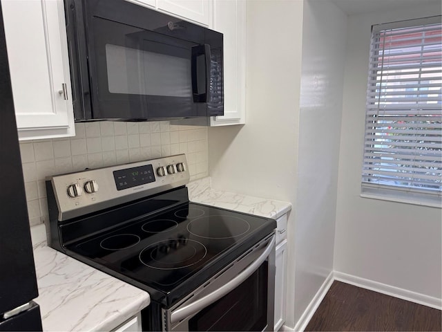 kitchen featuring black microwave, baseboards, electric stove, white cabinetry, and backsplash