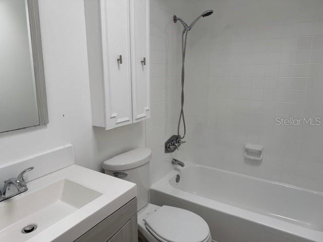 bathroom with washtub / shower combination, vanity, and toilet