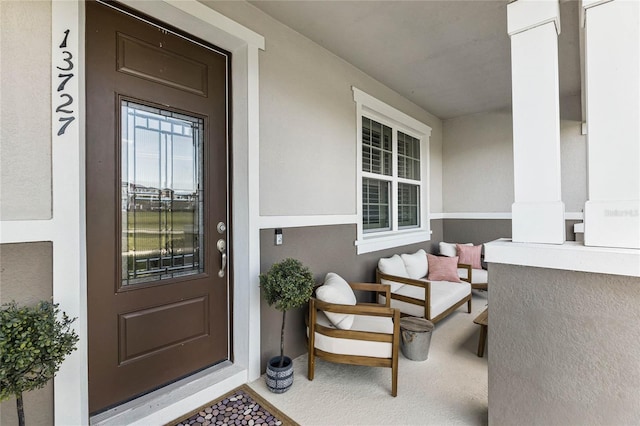 view of exterior entry featuring covered porch and stucco siding