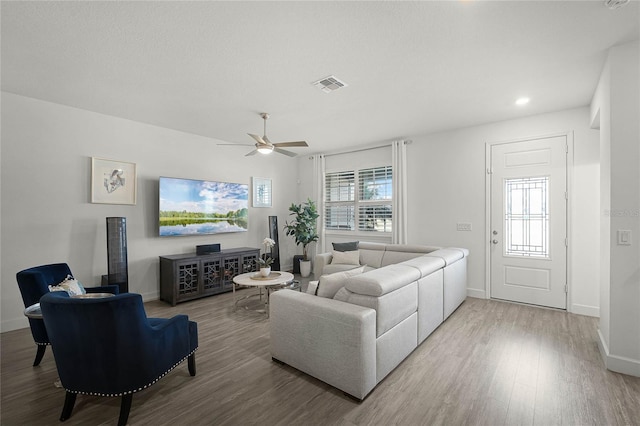 living room with baseboards, visible vents, ceiling fan, and wood finished floors