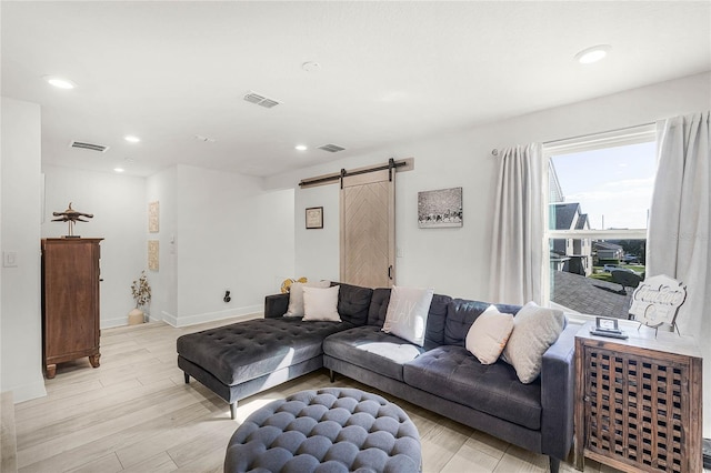 living area with light wood finished floors, a barn door, visible vents, and recessed lighting