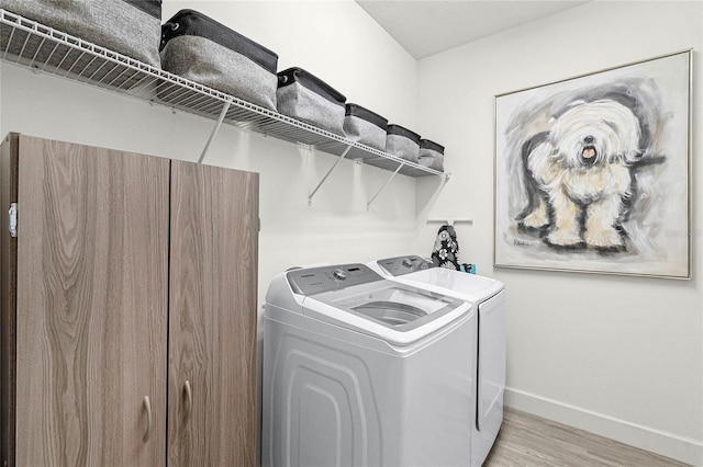 washroom with light wood-type flooring, laundry area, independent washer and dryer, and baseboards