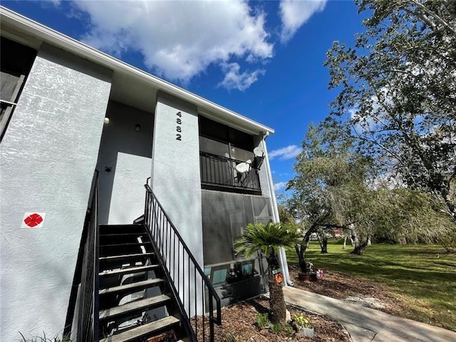 view of exterior entry with a yard and stucco siding