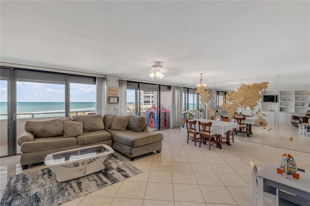 living room with light tile patterned floors, a water view, and a notable chandelier