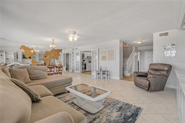 living area with light tile patterned floors, baseboards, visible vents, an inviting chandelier, and stairs