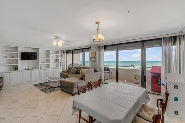 interior space with light tile patterned floors, built in shelves, ceiling fan with notable chandelier, and a water view