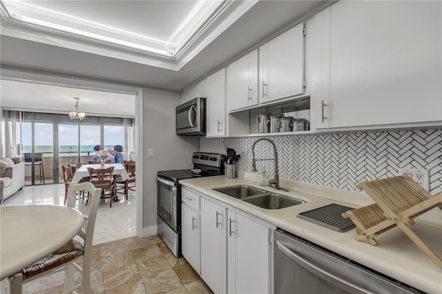 kitchen with a sink, light countertops, ornamental molding, appliances with stainless steel finishes, and decorative backsplash