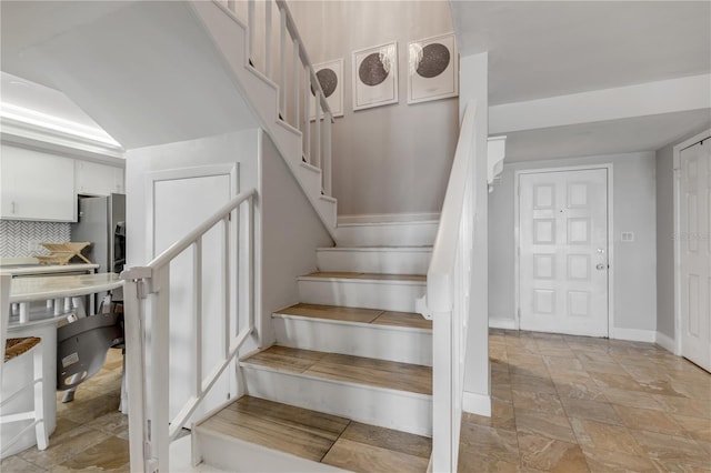 staircase featuring stone finish floor and baseboards