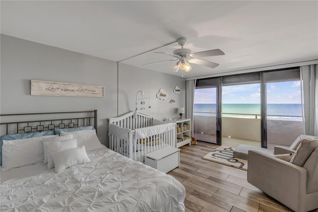 bedroom featuring a water view, wood finished floors, and a ceiling fan