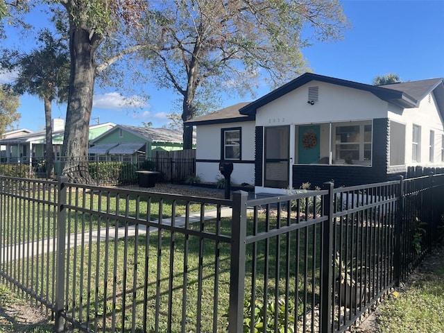 bungalow-style home featuring a fenced front yard, a porch, a front lawn, and stucco siding