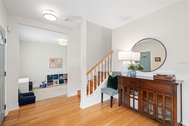 foyer entrance featuring stairs, baseboards, and wood finished floors