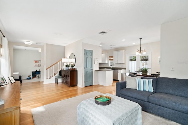 living room featuring recessed lighting, visible vents, stairs, light wood finished floors, and an inviting chandelier