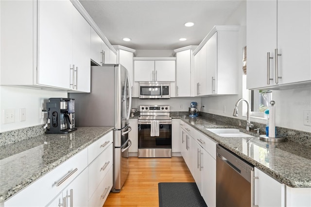 kitchen featuring recessed lighting, appliances with stainless steel finishes, white cabinets, a sink, and light wood-type flooring