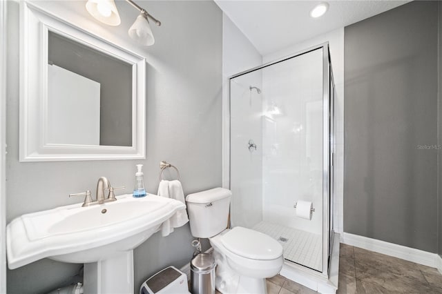 bathroom featuring baseboards, toilet, tile patterned flooring, a shower stall, and a sink