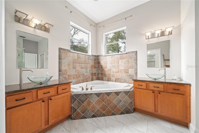 full bath with two vanities, marble finish floor, a garden tub, and a sink