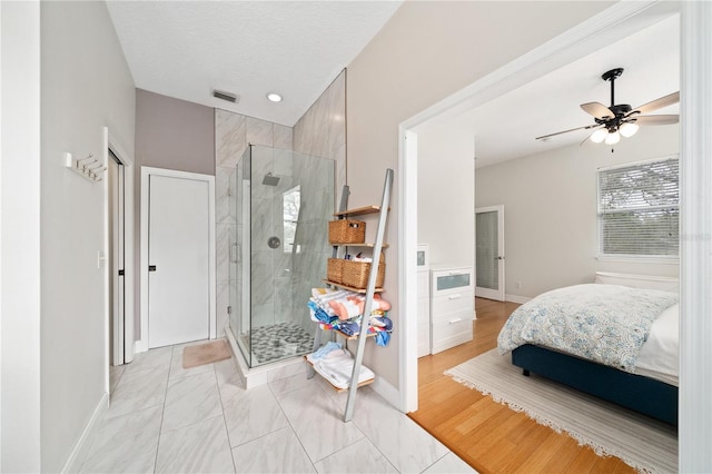 ensuite bathroom with a textured ceiling, ceiling fan, a shower stall, and baseboards