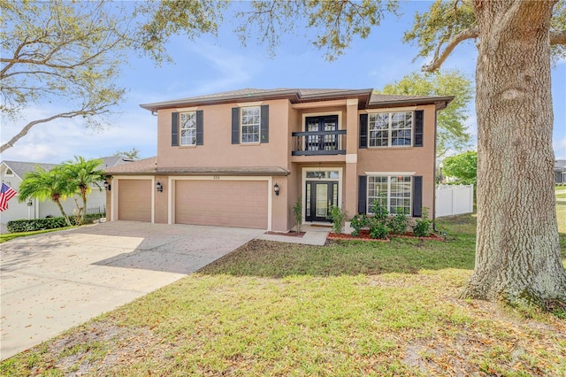 view of front of property featuring a balcony, fence, concrete driveway, stucco siding, and a front lawn