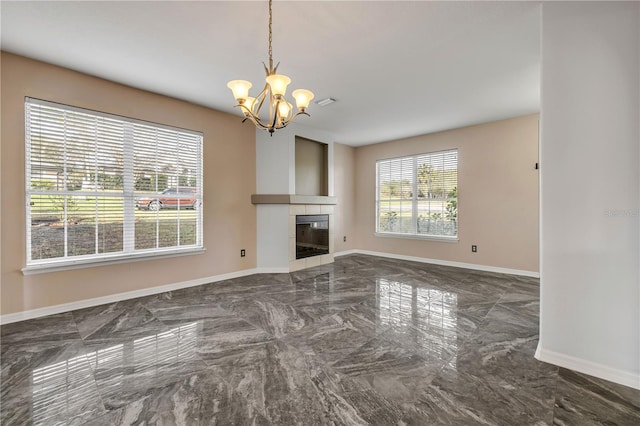 unfurnished living room featuring marble finish floor, baseboards, a tiled fireplace, and an inviting chandelier