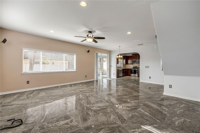 unfurnished living room with baseboards, arched walkways, a ceiling fan, marble finish floor, and recessed lighting