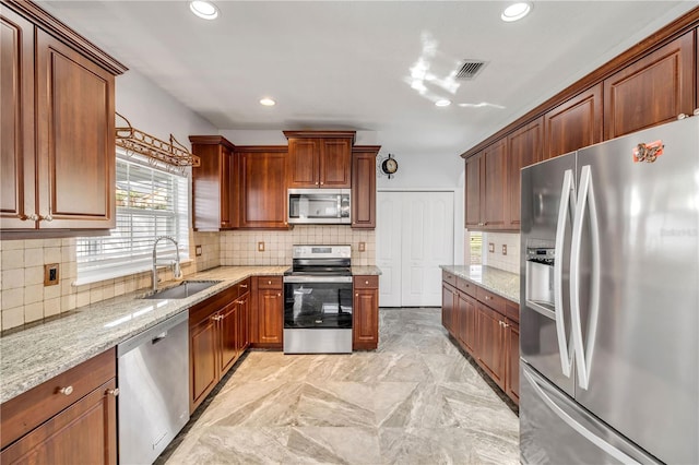 kitchen with light stone counters, visible vents, backsplash, appliances with stainless steel finishes, and a sink