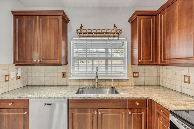 kitchen featuring light stone countertops, decorative backsplash, stainless steel appliances, and a sink