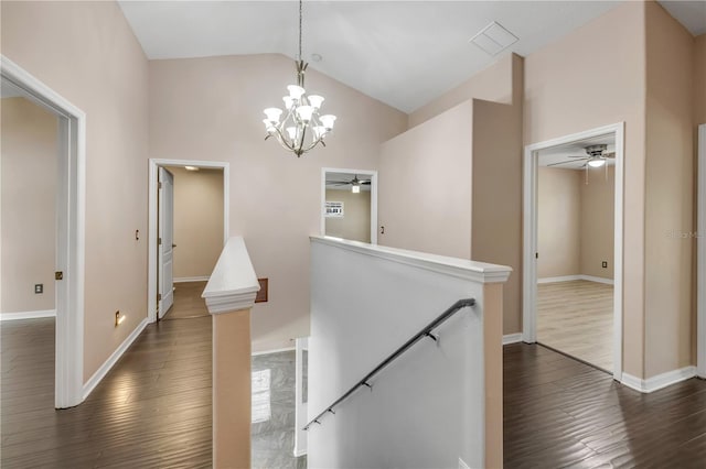 hall featuring dark wood-type flooring, baseboards, visible vents, and an upstairs landing