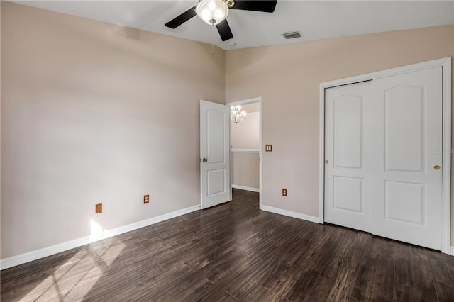 unfurnished bedroom with a closet, visible vents, dark wood-type flooring, vaulted ceiling, and baseboards