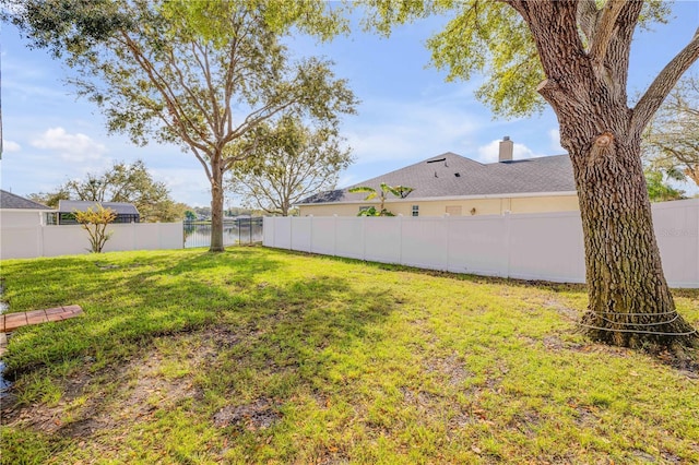 view of yard with a fenced backyard and a water view