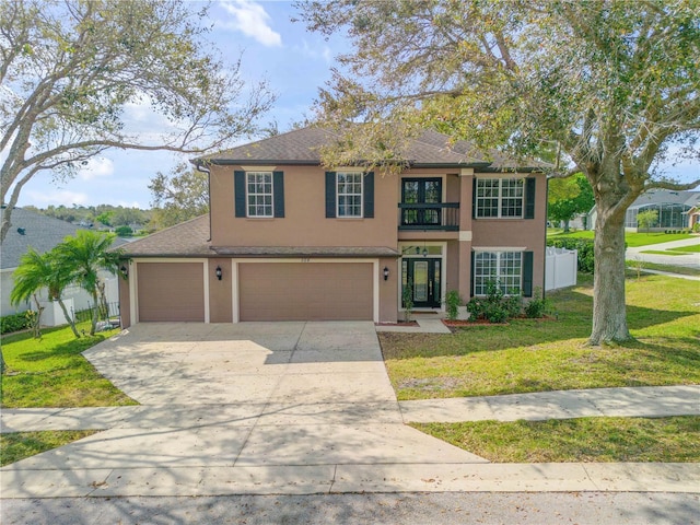 view of front of house featuring stucco siding, fence, a balcony, driveway, and a front lawn