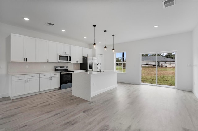 kitchen featuring visible vents, decorative backsplash, appliances with stainless steel finishes, white cabinetry, and a sink